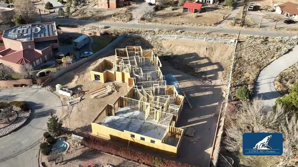 Aerial orbit of a Lowe-Bo Homes custom house early in framing on a hillside lot